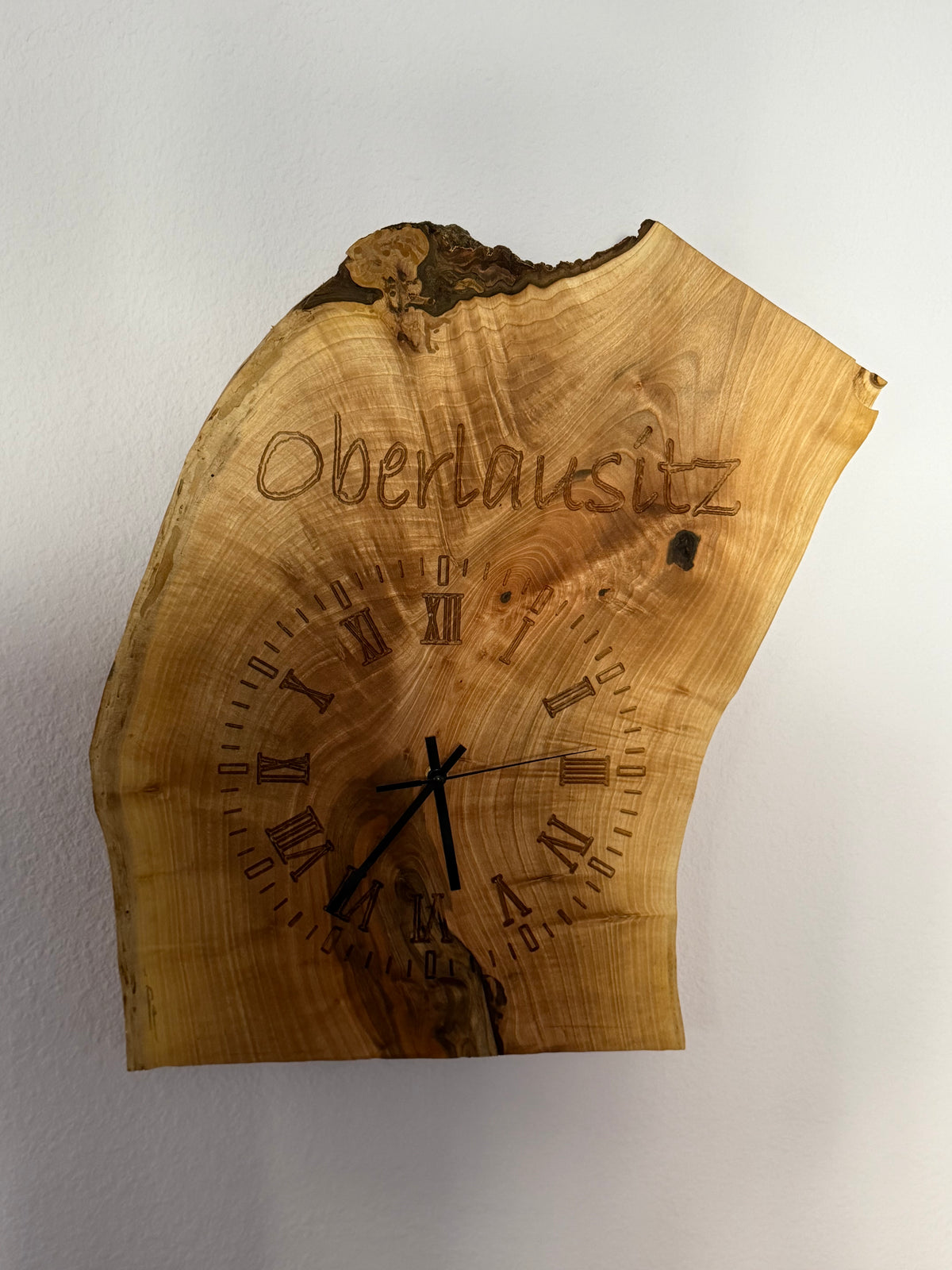 Handgefertigte Wanduhr Oberlausitz aus Massivholz mit natürlicher Baumkante, römischen Ziffern und Holzgravur von HLZ-Werkstatt.